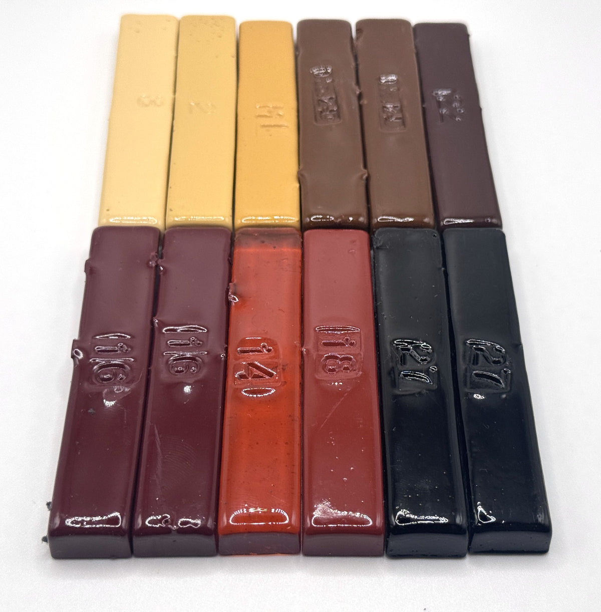 The Repair Dozen — twelve vintage hand-poured Merit burn-in half sticks standing upright in a kit box, furniture repair tones from blonde maple to jet black