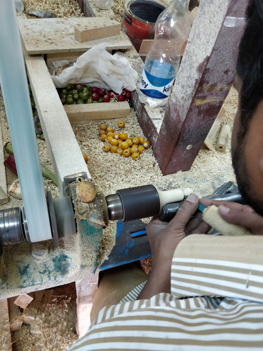 A Channapatna artisan coloring a turned toy with a stick of lac at the lathe. Photo: Kartik Mistry, Wikimedia Commons, CC BY-SA 4.0