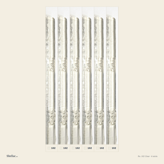 Six Merit No. 102 Clear burn-in sticks side by side — water-clear resin, embossed color number visible